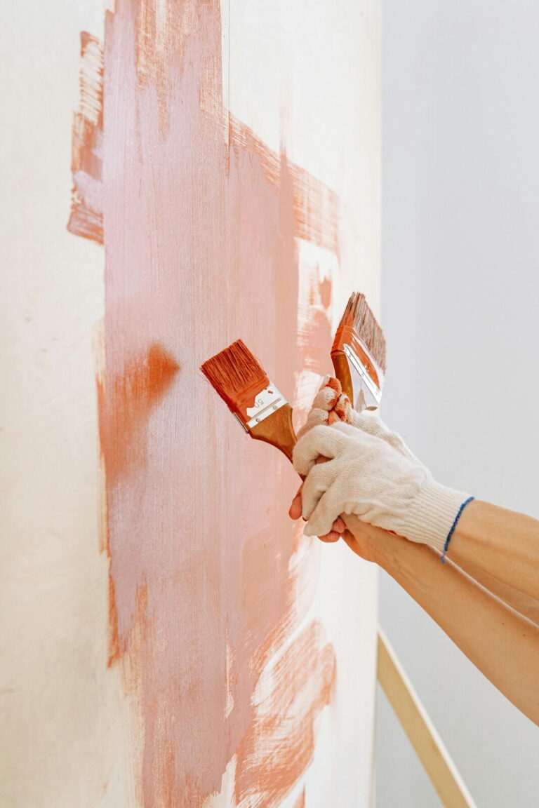 Brocha aplicando pintura en pared con distintos acabados visibles